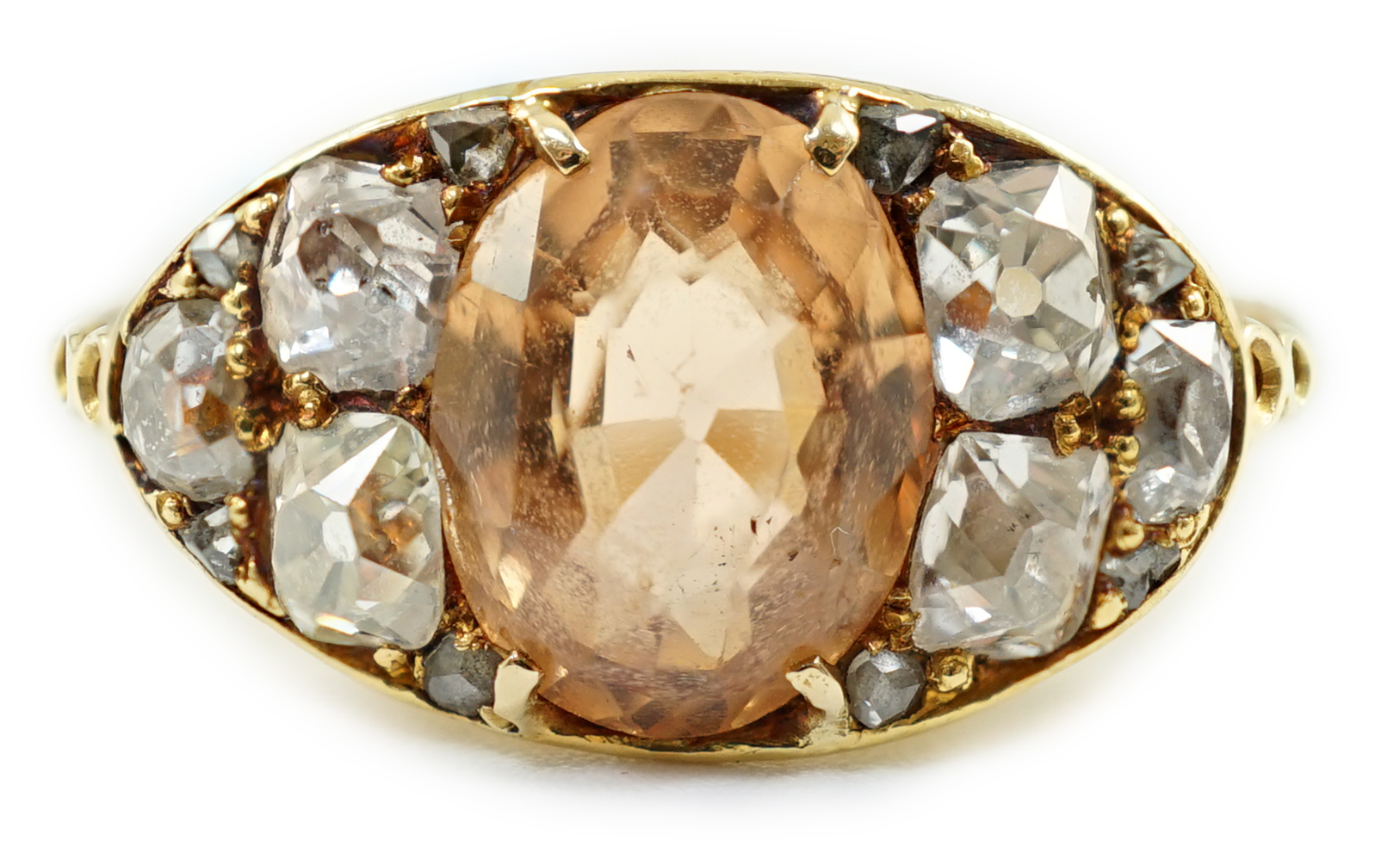 A 1940's gold and single stone oval cut orange topaz set ring, with six stone old mine cut diamond set shoulders